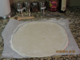Crust hand formed on parchment paper for transfer to pizza peel.