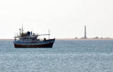 A small fishing boat with Berberas lighthouse