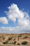 White puffy clouds in the blue sky over the desert hills