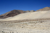 Sand dunes at the base of the mountains covering the rock desert floor