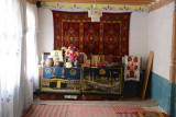The first room of the Jamaat Khana of Langar with a fine carpet on the wall and an interesting collection on the table