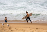 Surfer running along beach