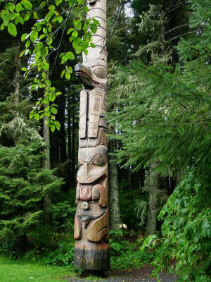A totem peaks out of the forest in Sitka, AK