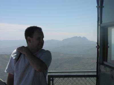 Aaron with 4-peaks in background on top of Forest Lookout Tower