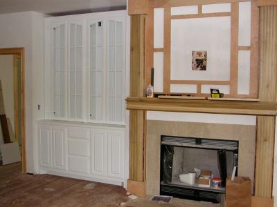 A cabinet appears next to the yet unfinished fireplace mantle