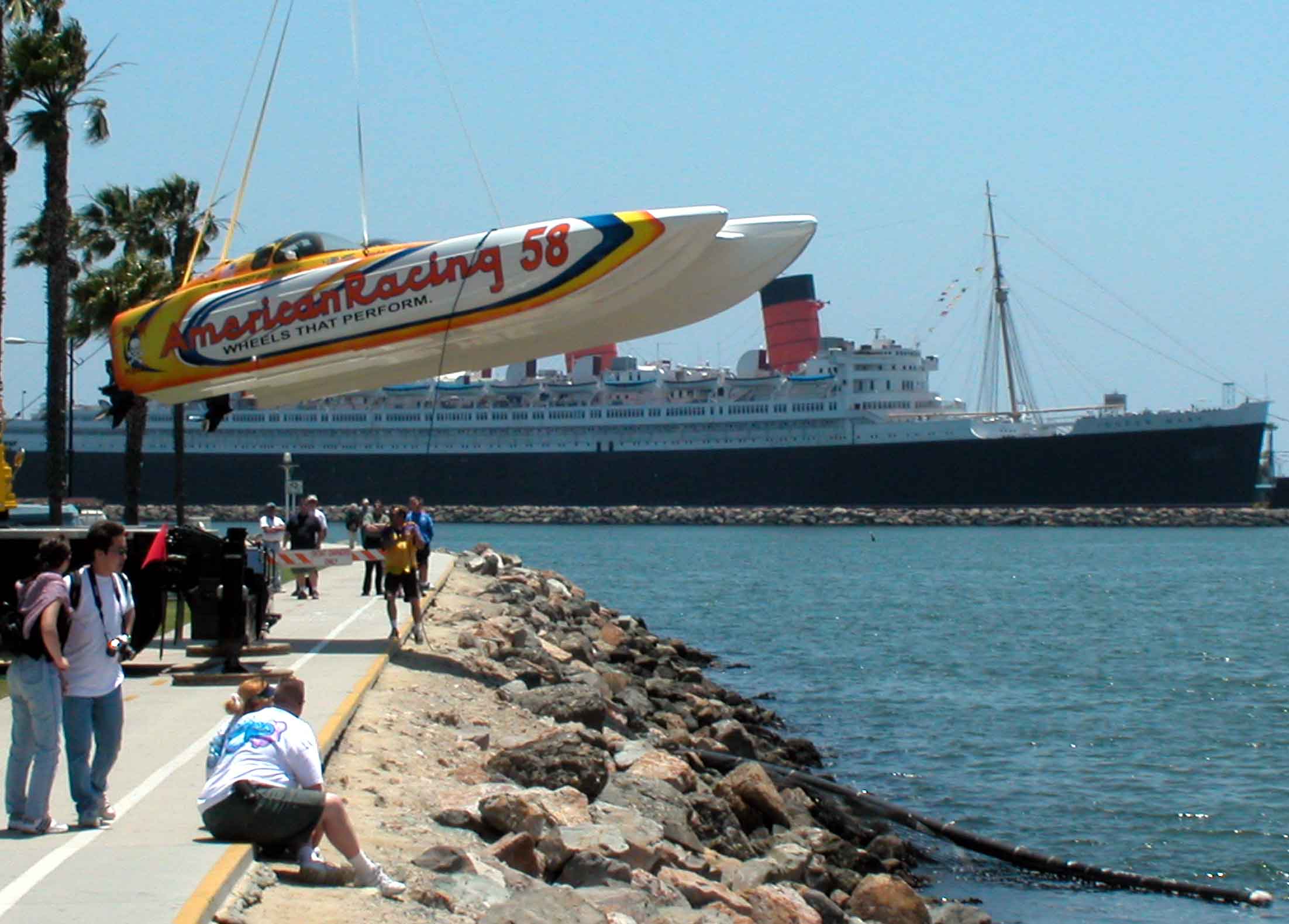 Racing boat being dropped by crane into water in front of Shoreline Village