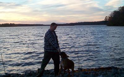 Chris and Biscuit by the lake playing tug of war with a stick.