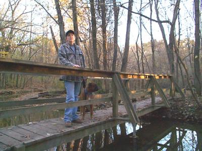 Kim and Biscuit on a bridge crossing a creek.