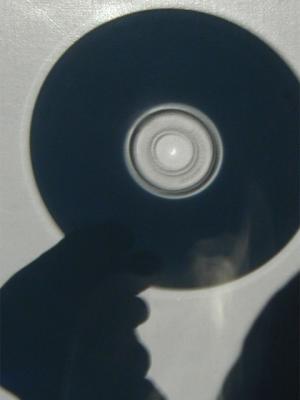 Projected image of partial solar eclipse using a CD as the mask. Image of sun visible as bright crescent inside the center hole. Cropped, unadjusted.