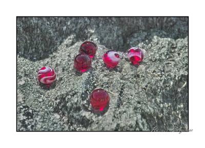 6 red marbles in water on granite