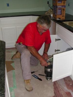 Electrician installs disposal unit under sink
