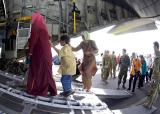 Tsunami victims board a C-130 Hercules