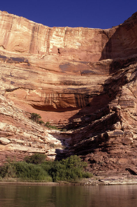 Sandstone wall towers above river.