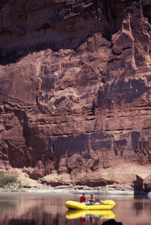 Raft travelers dwarfed by canyon wall.