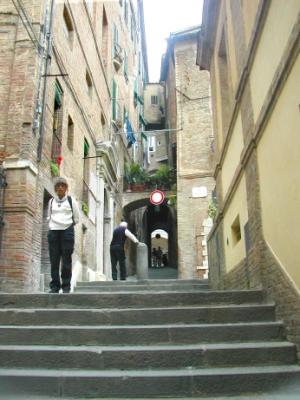Judy on a passageway in the Jewish quarter. The Great Synagogue of Siena is seen in white on the left. Built in the 1750's.