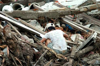 Asian Tsunami-Indonesian man looks through debris