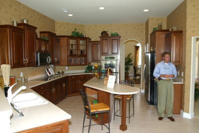 View of the kitchen from breakfast nook. Family room to the left, formal living room to the right. The fireplace will be on the right wall where you now see a refrigerator.