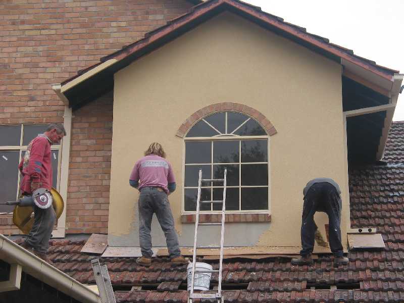 continuing to apply top coat of render