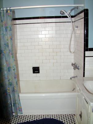Original bath tub.  The grout between the tiles have deteriorated to the point that it lets water through into the wall cavity and down to the kitchen!