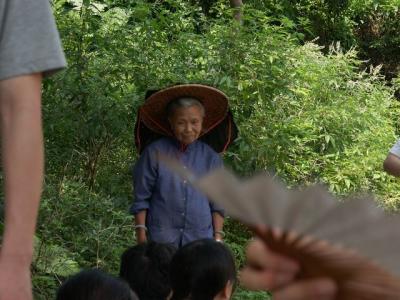 a graceful local elderly, among a group of hikers visiting her home village