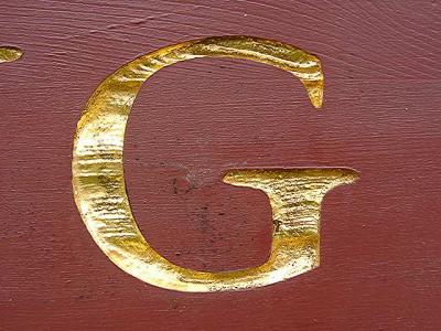 sign detail - letters seem to be sandblasted into the wood and gilded