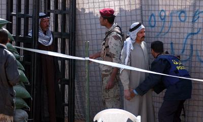 An Iraq policeman searches a voter