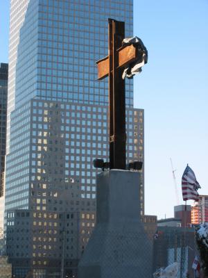 Workers left behind a metal beam structure in the shape of a cross.