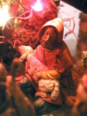A shepherd kneels behind the manger