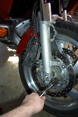 Loosening axle clamp bolts. Notice caliper is supported with bungee to reduce stress on brake lines.