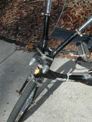 Note the two spring arbors with the conical, chromed covers pointing rearward, and mounted left and right of the steering tube's head badge.  These allow the praying mantis type handlebars to spring-load to the outside of the bike in order to damp shock transmission originating from the front axle. (This is, at first, most disconcerting to the rider who is unaccustomed to this bicycle).  I can best describe the handling as being something akin to holding the reins of a horse...that is to say, the rider must hold them firmly and up, off of the neck,  neither pulling too hard nor allowing them to slacken.