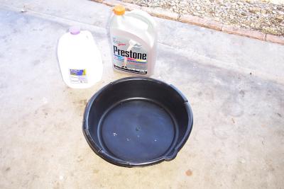 New antifreeze, distilled water, and clean drain pan at the ready