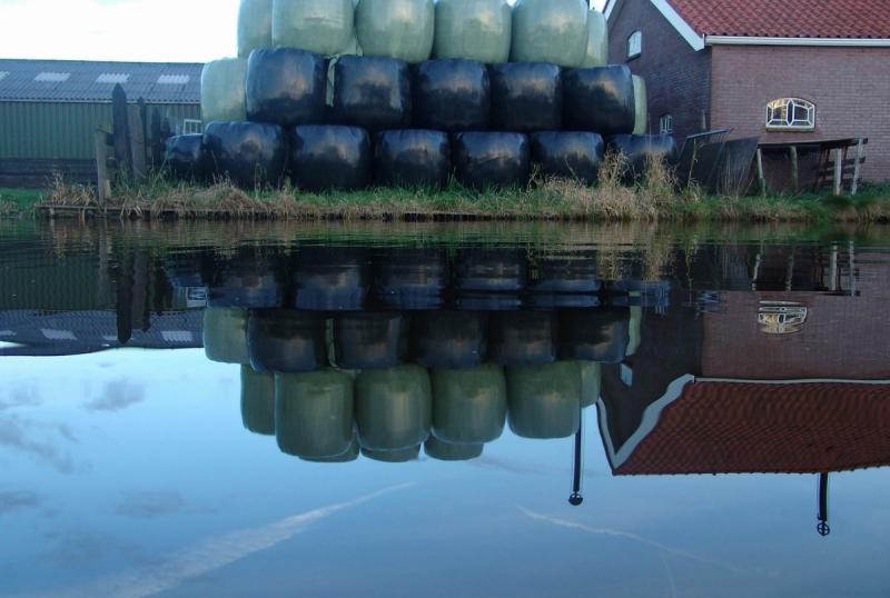 Reflection of farmhouse with haybags