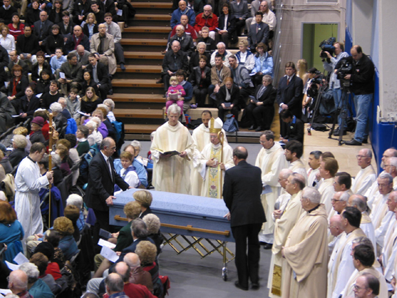 Bishop blesses casket with the media in background