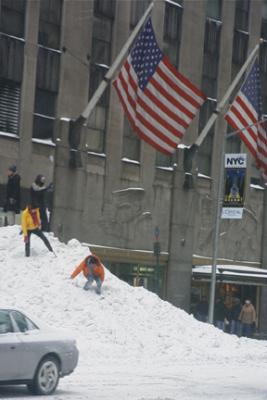 Two intrepid climbers scale a massive pile of snow near Radio City Music Hall
