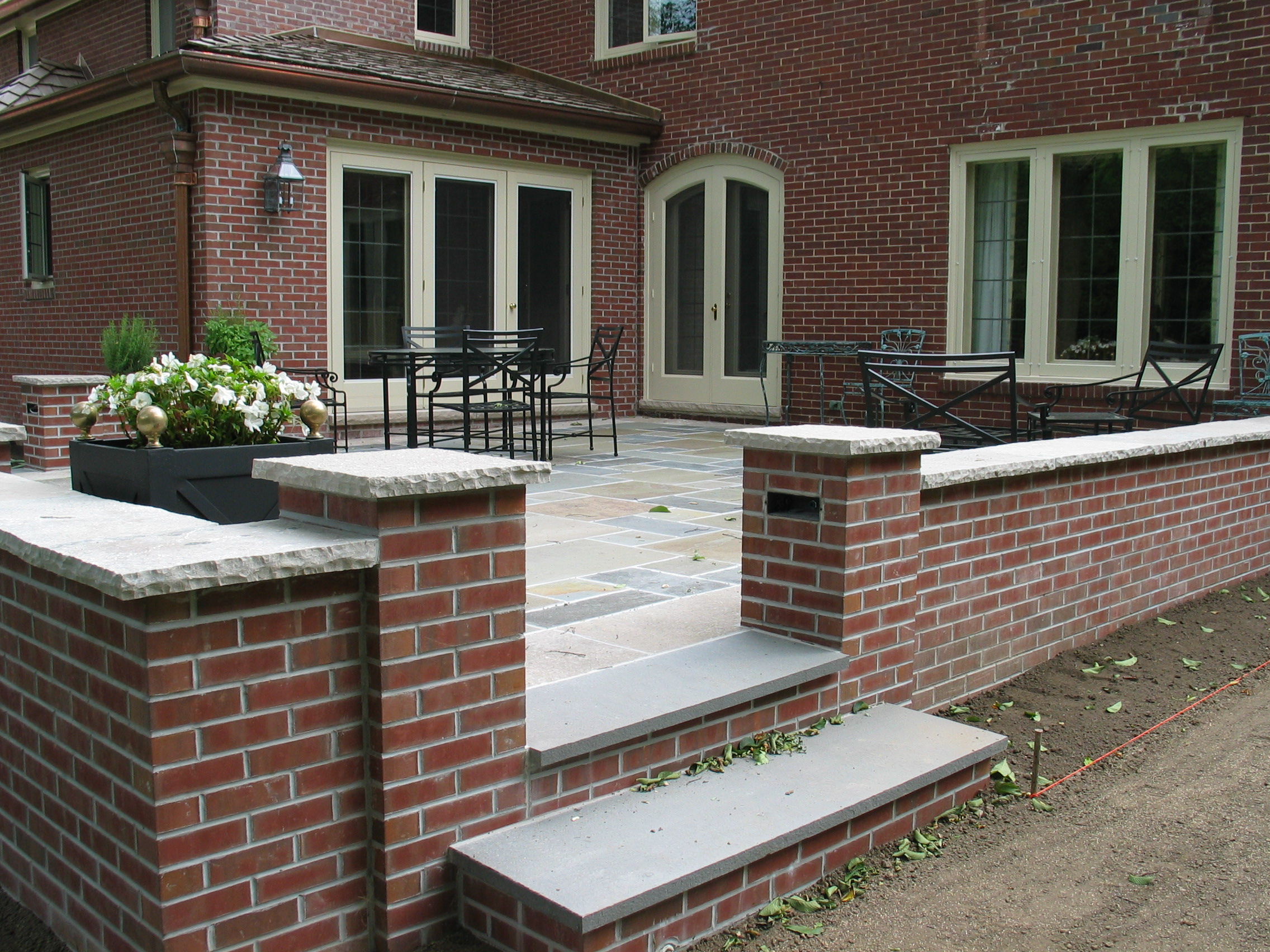 brick wall to match the house and edan stone cap frameing bluestone patio