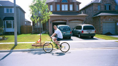 Peter riding past our house, the one with the no kids but two minivans!