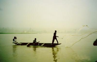 Fishermen in a pirogue casting their net