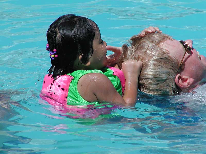 The Watermelon Girl hangs on to her dad for dear life.