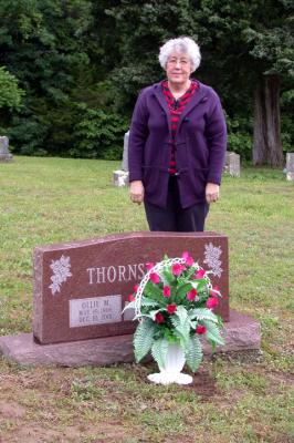 Mary standing behind the grave stone of her parents.