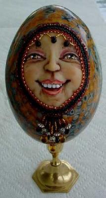 Decorative hand beading surround her happy face and she is enthroned on a brass candlestick holder