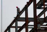 Closeup of workers walking on girders during construction of an addition to Kent Hall - Kent State University 6-03