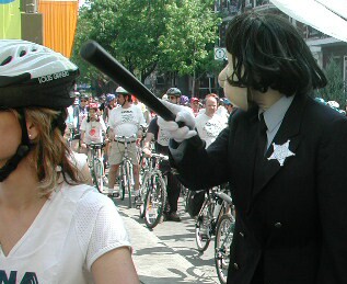 Lady cop tour character isn't having any of it from the crowd.  She has a night stick and she means business!(2003 Tour de L'lle)