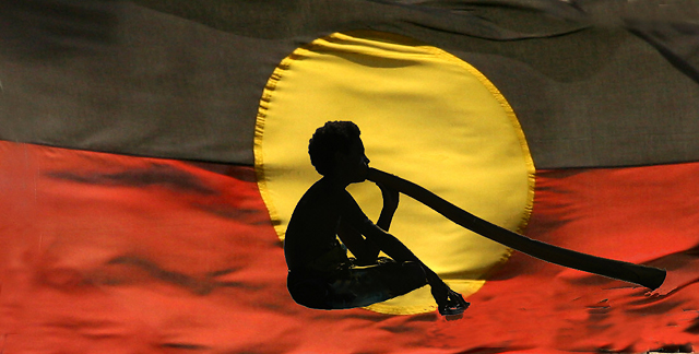 Aboriginal flag with didgeridoo busker in silhouette