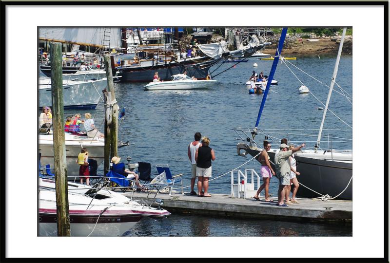 People line the harbor to watch. The lucky ones watch from their own boats.