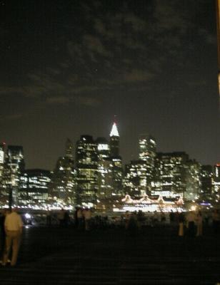 Bicycles line the rails and riders enjoy the lights of the Emerald City across the East River at the Fulton Ferry Landing, beneath the Brooklyn Bridge....