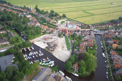 Birds eye view of IJlst. Church on the left is Ned. Hervormde Kerk. In the centre the (obsolete) Nooitgedacht factory is visible, complet with mural painting