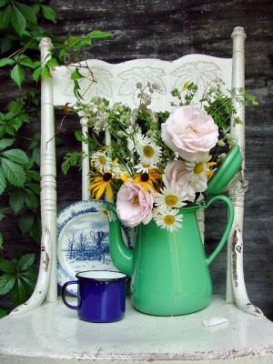 flowers in a coffee pot on a farm chair