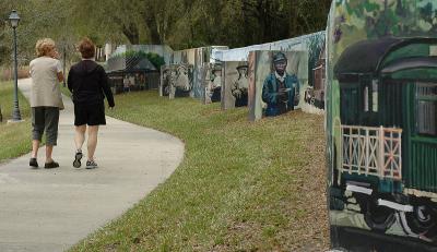 Sisters walk along Painters Pond mural