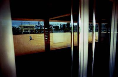 Reflected in his school's glass doors, a young baseball player runs laps as incentive to pay attention at spring training