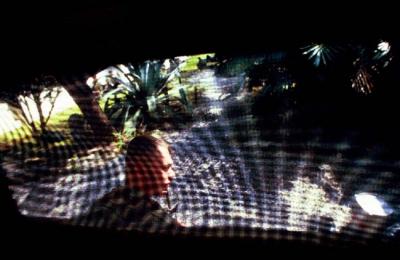 Seen through a screen window, a US Marine relaxes before an embassy evacuation drill